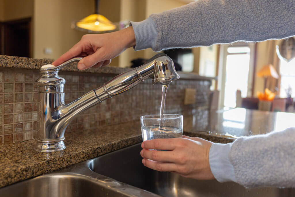 Woman Fills Cup Of Water At Kitchen Faucet | Plumbers 911 Boston | Contractor Referral Service