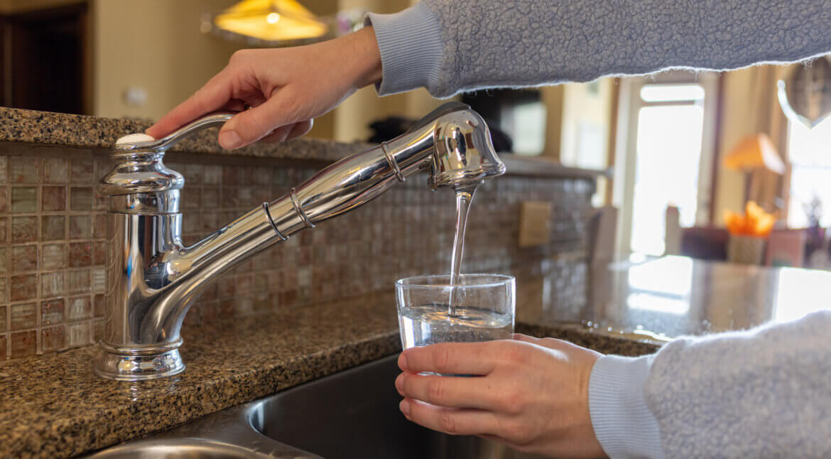Woman Fills Cup Of Water At Kitchen Faucet | Plumbers 911 Boston | Contractor Referral Service