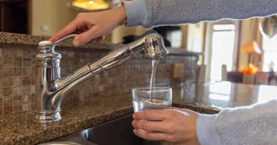 Woman Fills Cup Of Water At Kitchen Faucet | Plumbers 911 Boston | Contractor Referral Service